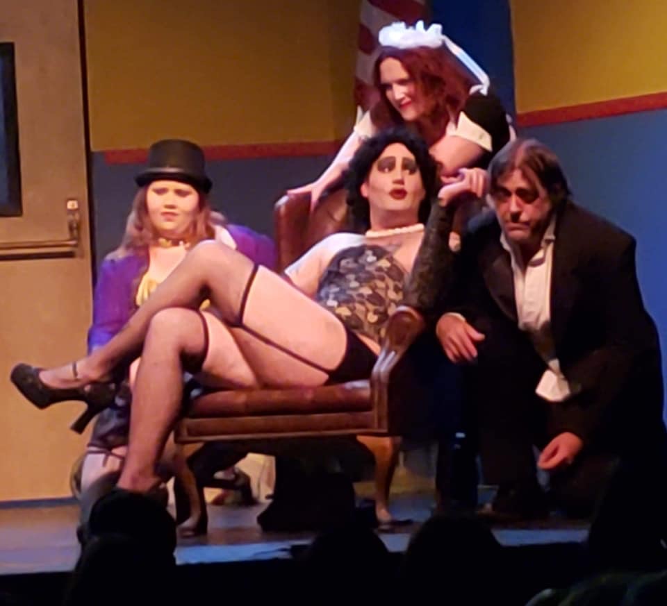 two drag queens and woman dressed like penguin from batman and a very tired man in a suit