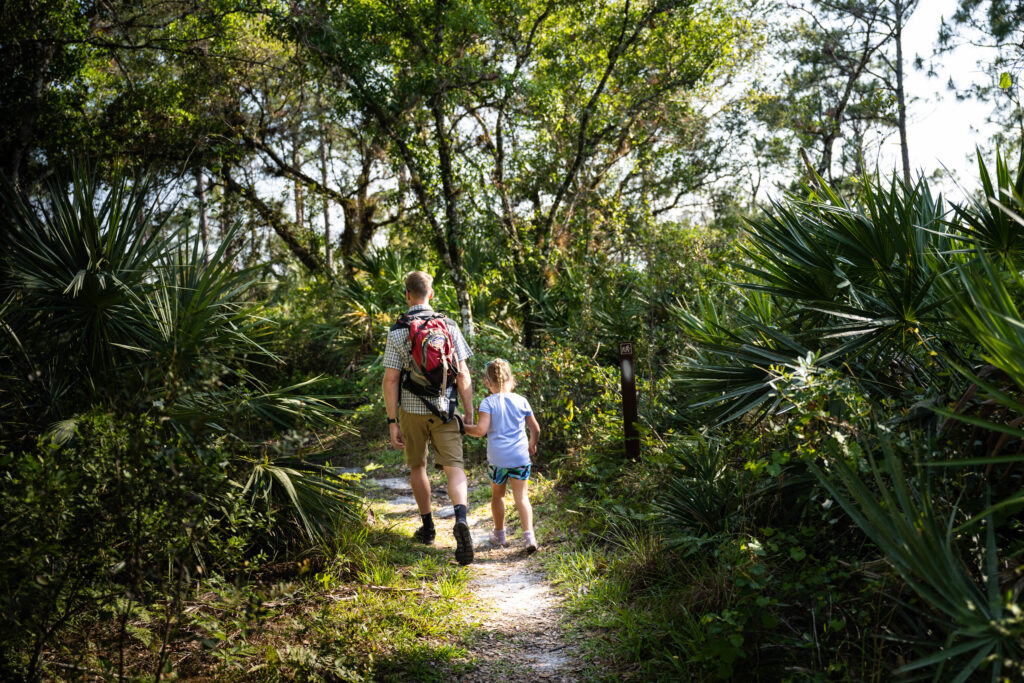Man and child hiking through Halpatiokee Park on an Explore Natural Martin free guided tour.