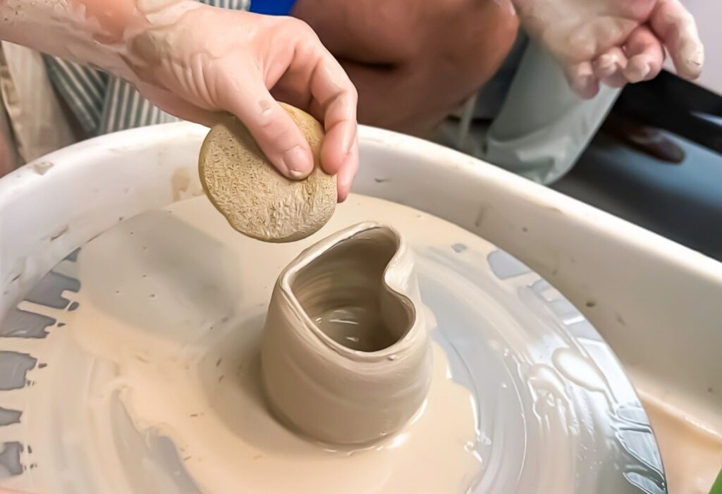 Hands making a heart-shaped clay sculpture.